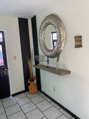 a mirror on a wall with a shelf and a window at Casa Jirafa. in Guadalajara