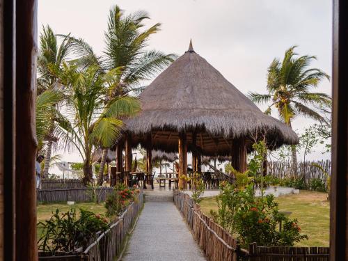 un pabellón con mesas, sillas y palmeras en Paraíso Natural Ecohotel en San Bernardo del Viento
