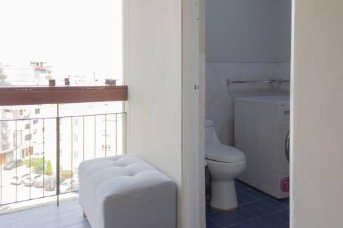 een witte badkamer met een toilet en een raam bij Departamento confortable en San Borja in Lima