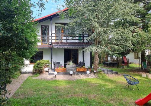 uma casa com varanda e uma árvore em Dom letniskowy Bajka em Rowy
