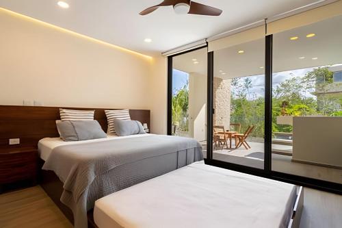 2 Betten in einem Schlafzimmer mit Blick auf eine Terrasse in der Unterkunft Moots Tulum in Tulum