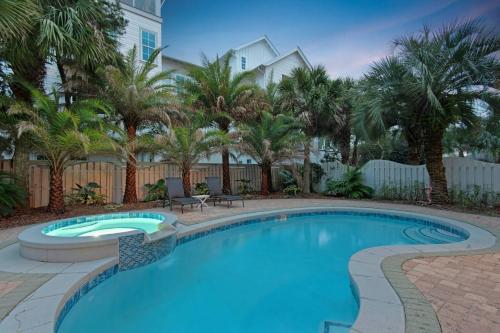 a swimming pool with palm trees and a building at A Point of View in Seagrove Beach