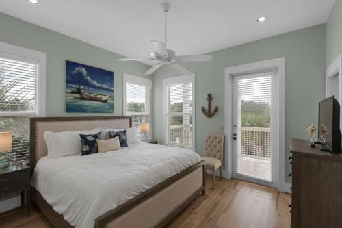 a bedroom with a bed with a ceiling fan and windows at A Point of View in Seagrove Beach