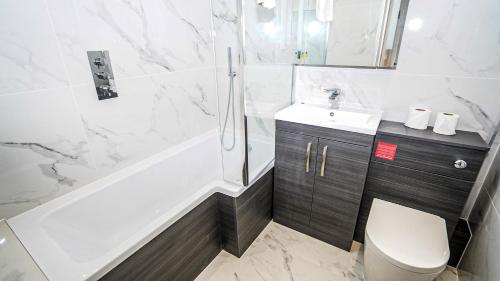 ein Badezimmer mit einer Badewanne, einem Waschbecken und einem WC in der Unterkunft 4-Bedroom, 3-Bath Home Sleeps 8 Free Parking in Farnham Royal