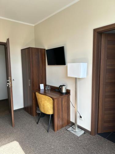 Habitación de hotel con escritorio con lámpara y TV en KOLONIA HOTEL en Świdnica