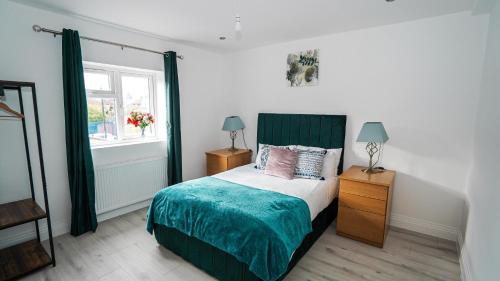 Schlafzimmer mit einem Bett mit einem grünen Kopfteil und einem Fenster in der Unterkunft 4-Bedroom, 3-Bath Home Sleeps 8 Free Parking in Farnham Royal