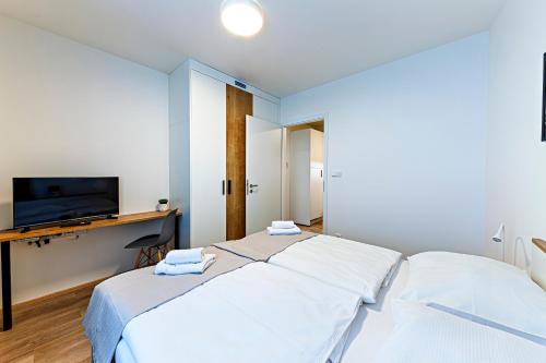 a bedroom with two beds and a desk with a television at Kora Apartments Andel in Prague