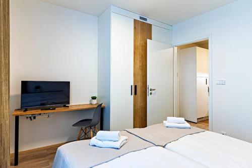 a bedroom with a bed and a desk with a television at Kora Apartments Andel in Prague