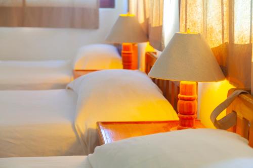 a bedroom with two beds and a table with two lamps at Hotel Casa Rush in Puerto Ángel