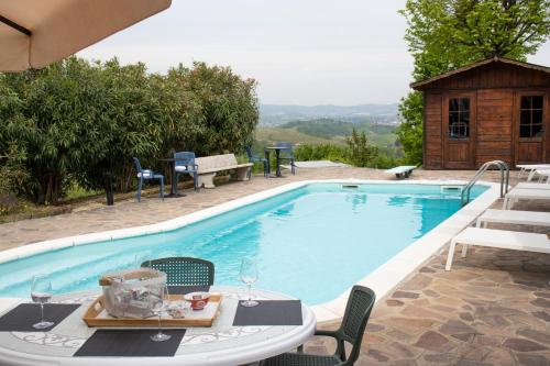 einen Tisch und Stühle neben einem Pool in der Unterkunft Villa Magna with pool Alba Hills in Govone