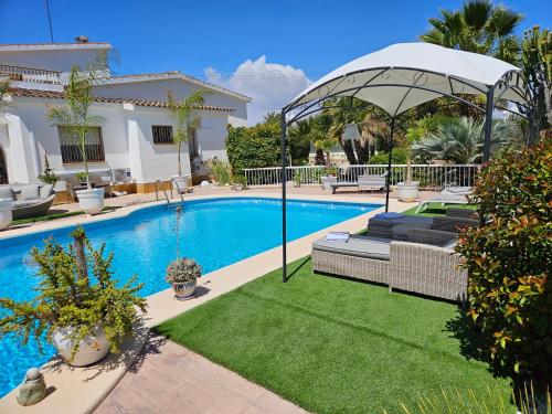 une maison avec une piscine entourée d'une pelouse et d'un parasol dans l'établissement Romantico Wellness Casa Veronica, à Elche