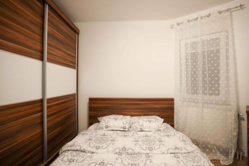 1 dormitorio con 1 cama con cabecero de madera en Troy’s Apartment, en Pristina
