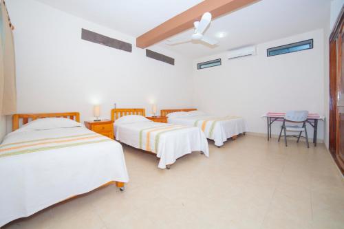 a room with three beds and a table in it at Hotel Casa Rush in Puerto Ángel