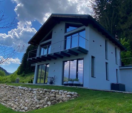 a white house with large windows and a stone wall at Bramble Chalet in Zărneşti