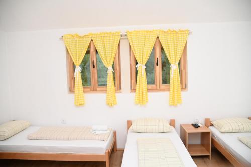 a room with two beds and a window with yellow curtains at Konak Dobri Potok in Krupanj