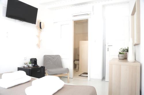 Habitación blanca con cama y silla en Whitelist Studios in Mykonos Town en Mykonos ciudad