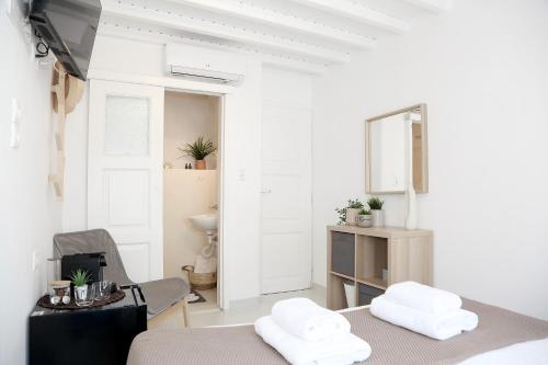 Habitación blanca con 2 camas y espejo. en Whitelist Studios in Mykonos Town en Mykonos ciudad