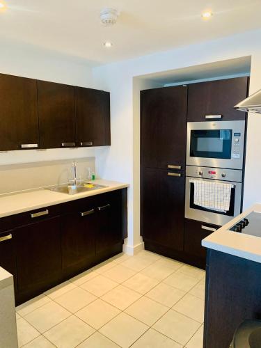 a kitchen with brown cabinets and a sink and a microwave at Victoria Rooms in Manchester