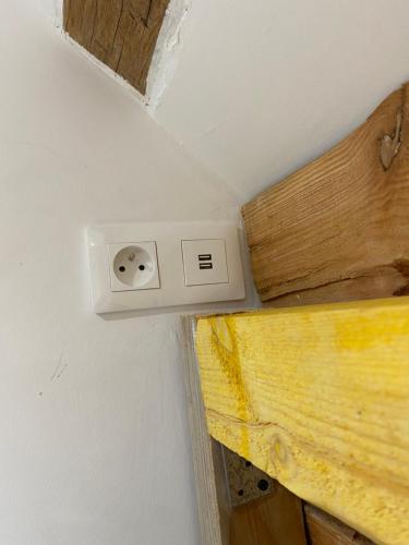 a white lightswitch on a wall next to a bed at La cabane in Aubigny-sur-Nère