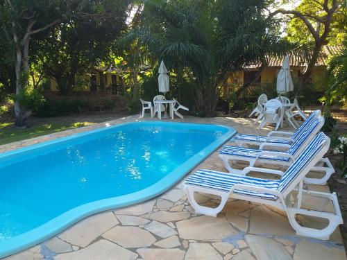 a swimming pool with lounge chairs and a table and chairs at Pousada Vila Imbassai in Imbassai