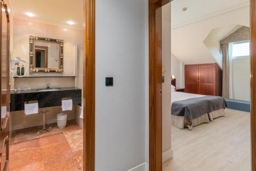 a bedroom with a bed and a bathroom with a sink at Hotel Spa Milagros Golf in Mogro