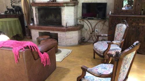 ein Wohnzimmer mit zwei Stühlen und einem Kamin in der Unterkunft Casa Sítio de sol in Penedo