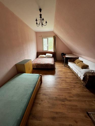 a attic room with two beds and a chandelier at Vasaras māja Rāzna - Pirts 