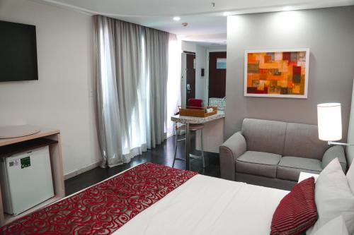 a hotel room with a bed and a couch at Comfort Suites Macaé in Macaé