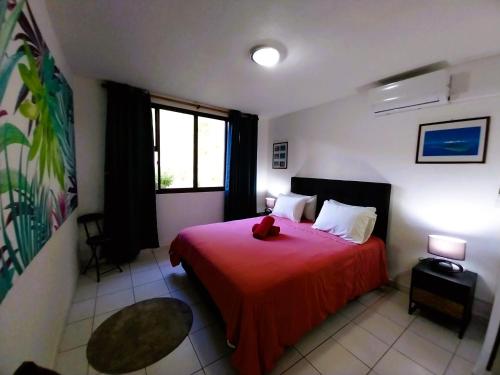um quarto com uma cama vermelha com um urso de peluche em TAHITI - Amoe Condo em Mahina