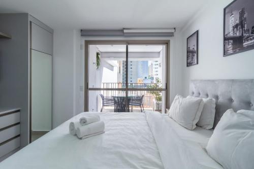 a bedroom with a large white bed with a balcony at 360 Mirant Vila Madalena in Sao Paulo