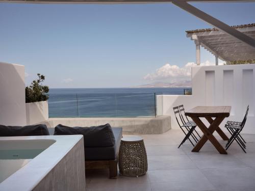 a patio with a table and chairs and a view of the ocean at Boheme Mykonos Town - Small Luxury Hotels of the World in Mýkonos City