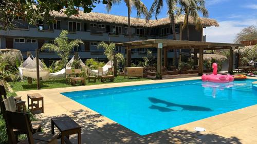 a swimming pool with a pink flamingo in front of a hotel at Straw Hat Surf Hostel & Bar in Brisas de Zicatela