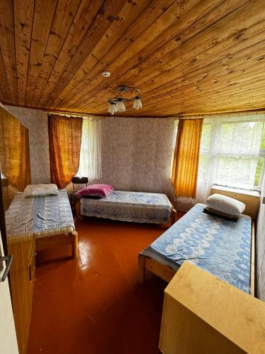 a room with three beds and a wooden ceiling at Vasaras mājiņa pie Rāznas ezera Nr 3 in Kaunata
