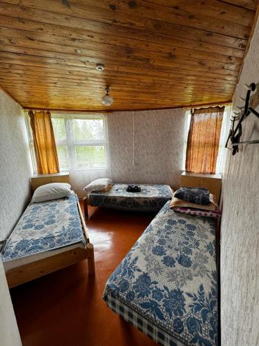 a room with three beds and a wooden ceiling at Vasaras mājiņa pie Rāznas ezera Nr 3 in Kaunata