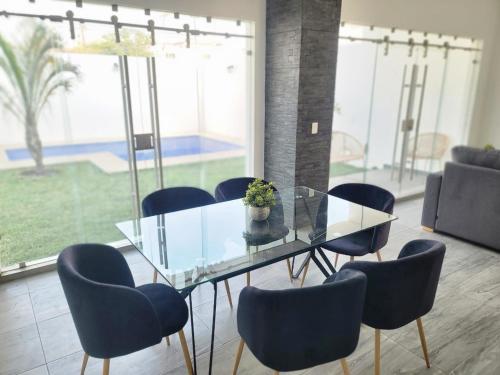 une salle à manger avec une table en verre et des chaises bleues dans l'établissement Casa Villa Teques, à Tequesquitengo