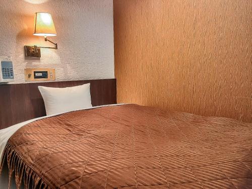 a bedroom with a bed with a brown blanket and a lamp at Hotel Sho Sapporo - Vacation STAY 55639v in Sapporo