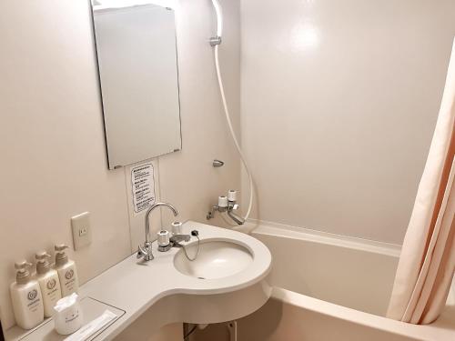 a white bathroom with a sink and a mirror at Hotel Sho Sapporo - Vacation STAY 55639v in Sapporo