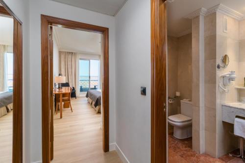 a bathroom with a toilet and a bedroom with a bed at Hotel Milagros Golf in Mogro