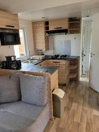 une cuisine avec un canapé au milieu d'une cuisine dans l'établissement Paradis Cap Ferret Location Mobil home Amira 42m2 ou Calina 31m2, à Lège-Cap-Ferret