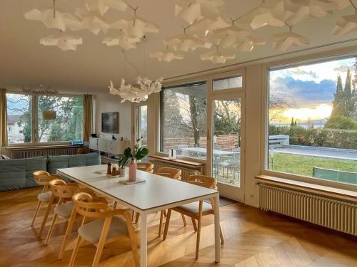 ein Esszimmer mit einem weißen Tisch und Stühlen in der Unterkunft Grande villa avec piscine in Neuenburg