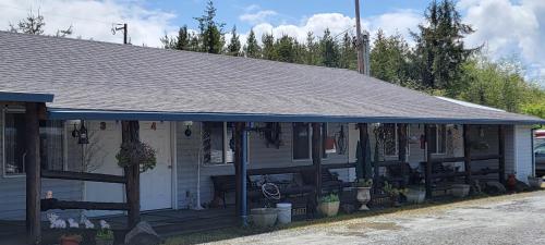 a white house with a blue roof with plants at The Bunkhouse Motel in Nehalem