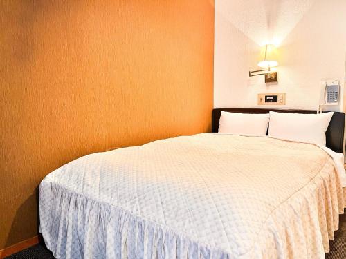 Hotel Sho Sapporo - Vacation STAY 53624v في سابورو: غرفة نوم بسرير ابيض بجدار برتقالي