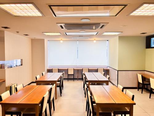 Hotel Sho Sapporo - Vacation STAY 53624v في سابورو: قاعة دروس فيها طاولات وكراسي خشبية ولوح أبيض