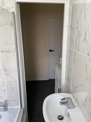 a white bathroom with a sink and a shower at Peeams abode in Dagenham