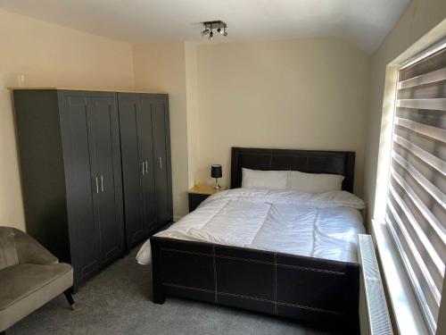 a bedroom with a large bed with black cabinets at Peeams abode in Dagenham