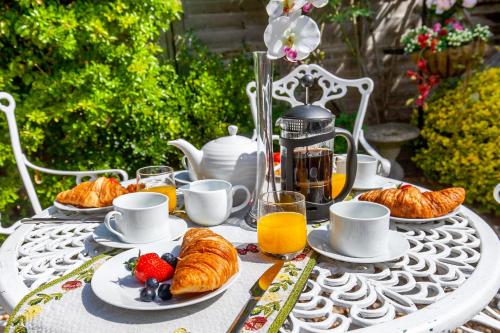 a table with plates of croissants and fruit on it at 2-Bedroom Stunning, Chic, Spacious & Stylish Retreat, Central Winchester, Free On-Street Parking, Sleeps 6, Pet-Friendly - by Blue Puffin Stays in Winchester