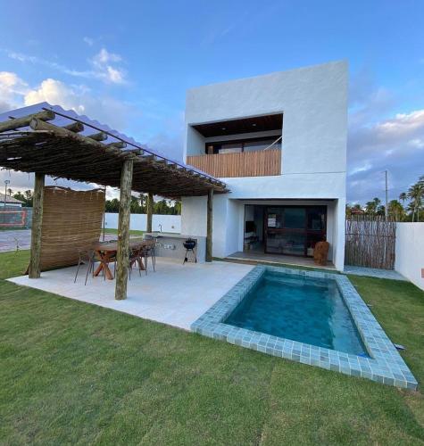 a backyard with a swimming pool and a house at Casa Pitanga - 150 mts do mar in Pôrto de Pedras