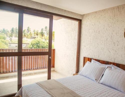a bedroom with a bed and a large window at Casa Pitanga - 150 mts do mar in Pôrto de Pedras