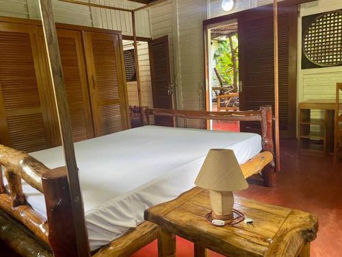 a bedroom with a bed and a table with a lamp at Maison meublée « valiha » in Hell-Ville