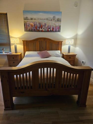 a large wooden bed in a bedroom with two lamps at Ard Aoibhinn Roscommon Bed & Breakfast in Lecarrow